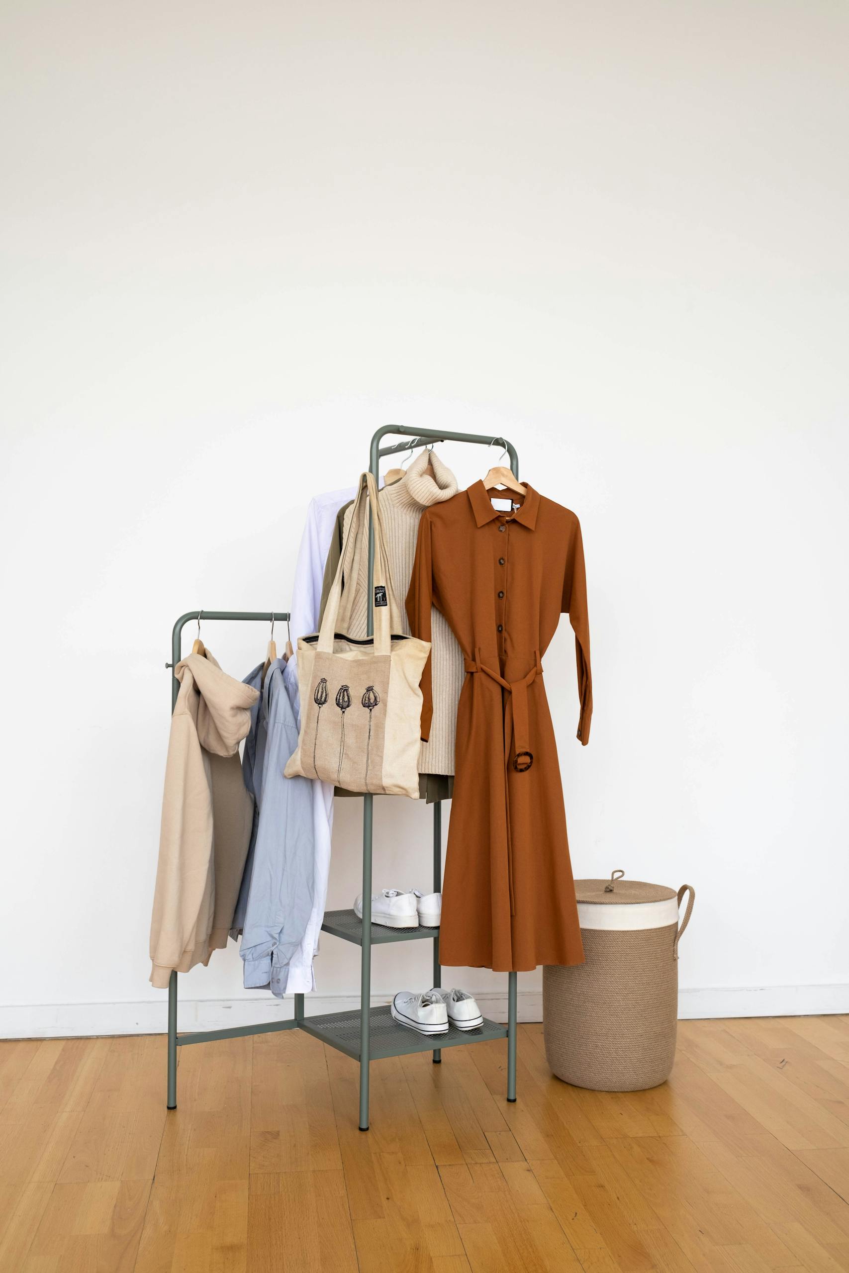 Stylish clothing and accessories neatly arranged on a minimalist metal rack indoors.